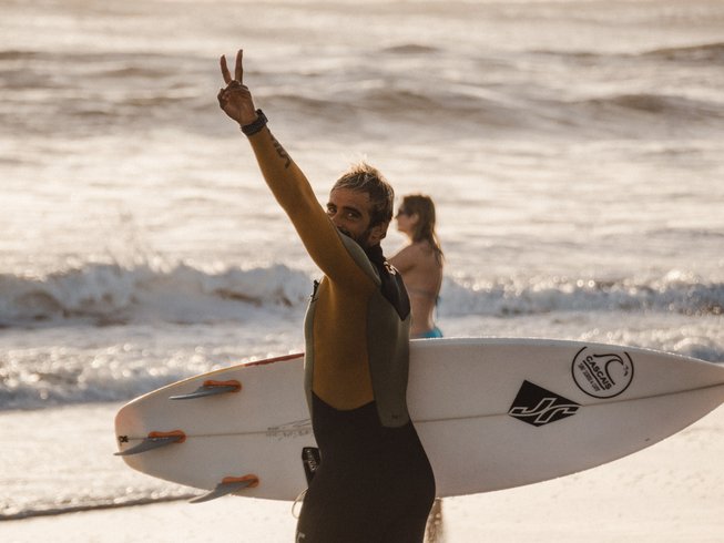 Surfer genietend van een golf bij zonsondergang in Cascais, Portugal