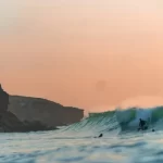 Surfen in Portugal met Ericeira op de achtergrond.