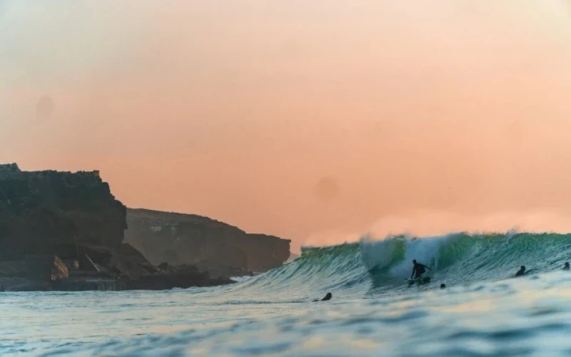Surfen in Portugal met Ericeira op de achtergrond. 